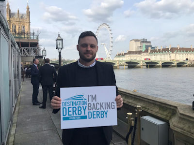 Ben Bradley MP holding an 'I'm backing Derby' sign