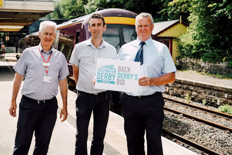 Derwent Valley Line Community Rail Partnership holding a 'Back Derby's Bid' sign at Matlock train station