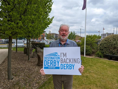 John Forkin holding an 'I'm backing Derby' sign