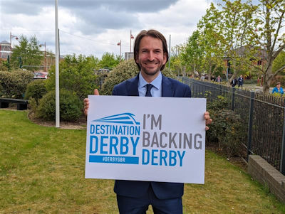 Nic Werran holding an 'I'm backing Derby' sign