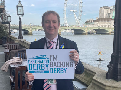 Nigel Mills MP holding an 'I'm backing Derby' sign