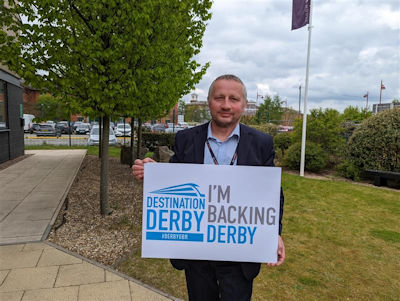 Richard Kelly holding an 'I'm backing Derby' sign