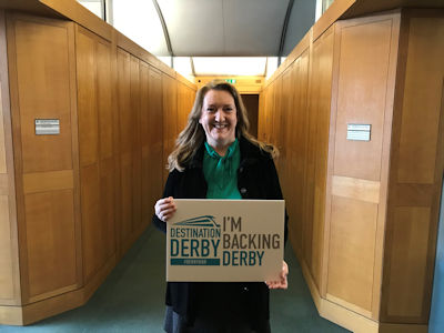 Sarah Dines MP holding an 'I'm backing Derby' sign